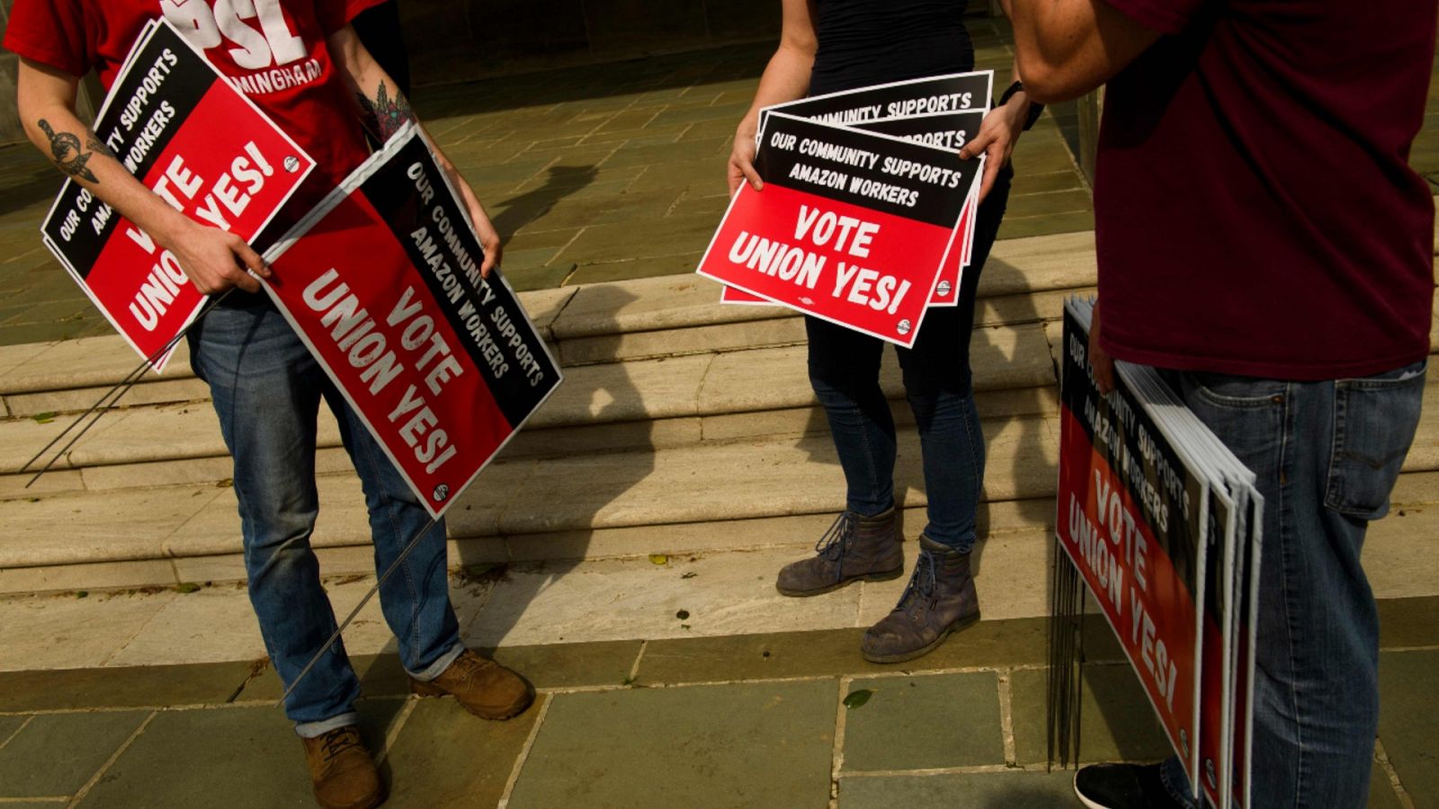 Imagen de archivo del 27 de marzo de 2021 de varias personas sujetando carteles donde se lee "Vote Union Yes!" ("Vota Sindicatos Si") durante una protesta en solidaridad con la sindicalización de los trabajadores del centro logístico de Amazon en Alabama.