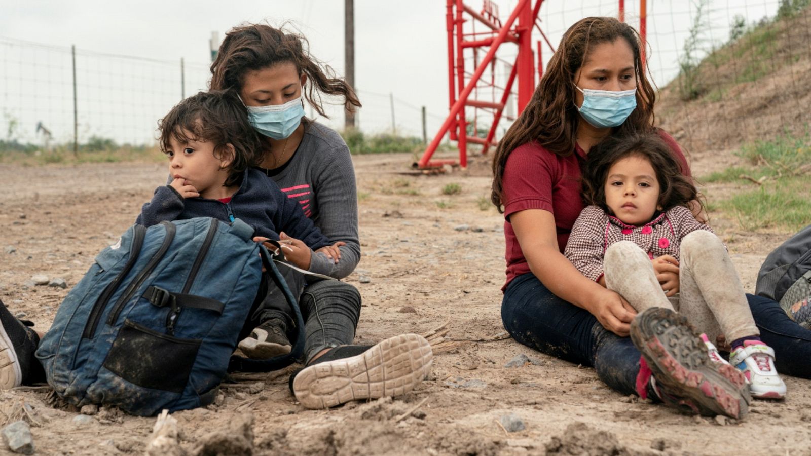 Una imagen del 27 de abril de 2021 que muestra a dos madres inmigrantes que buscan asilo sentadas junto a sus hijos mientras esperan ser transportadas por la Patrulla Fronteriza de EE.UU. tras cruzar el río Grande hacia los Estados Unidos desde México.