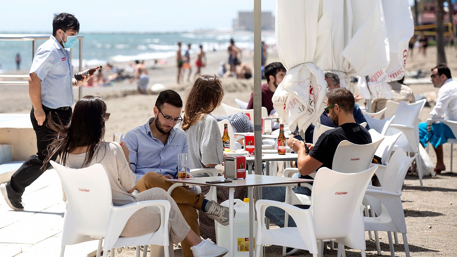 Varias personas disfrutan del buen tiempo en los chiringuitos de la playa de La Misericordia de Málaga.
