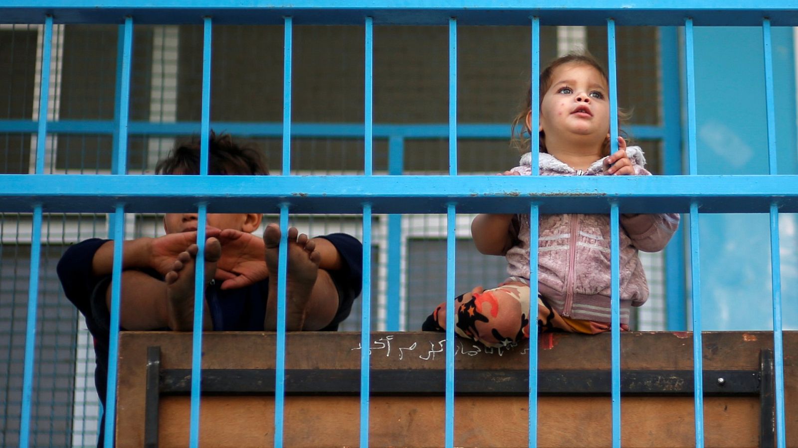 Un niño y una niña mirando por la ventana en el norte de Gaza