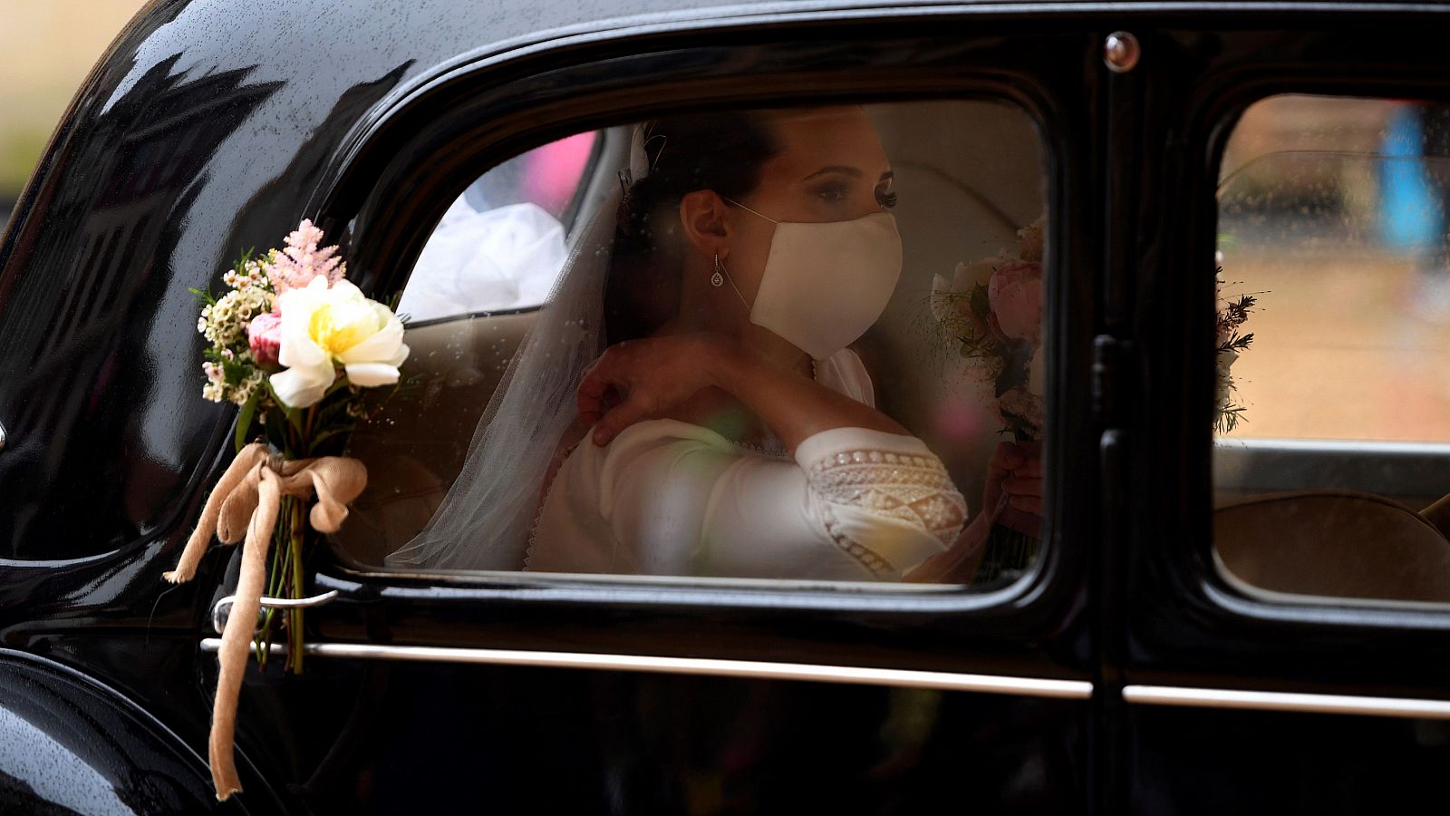 Una novia llega en coche con su mascarilla para su boda en el Ayuntamiento de Oviedo.