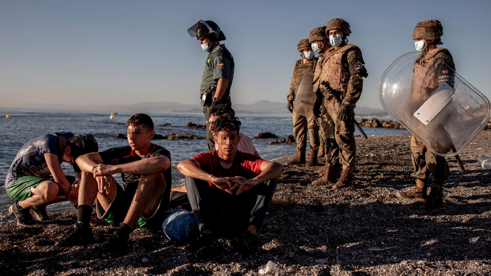Miembros del ejército observan a un grupo de menores migrantes a su llegada a Ceuta el pasado mes de mayo