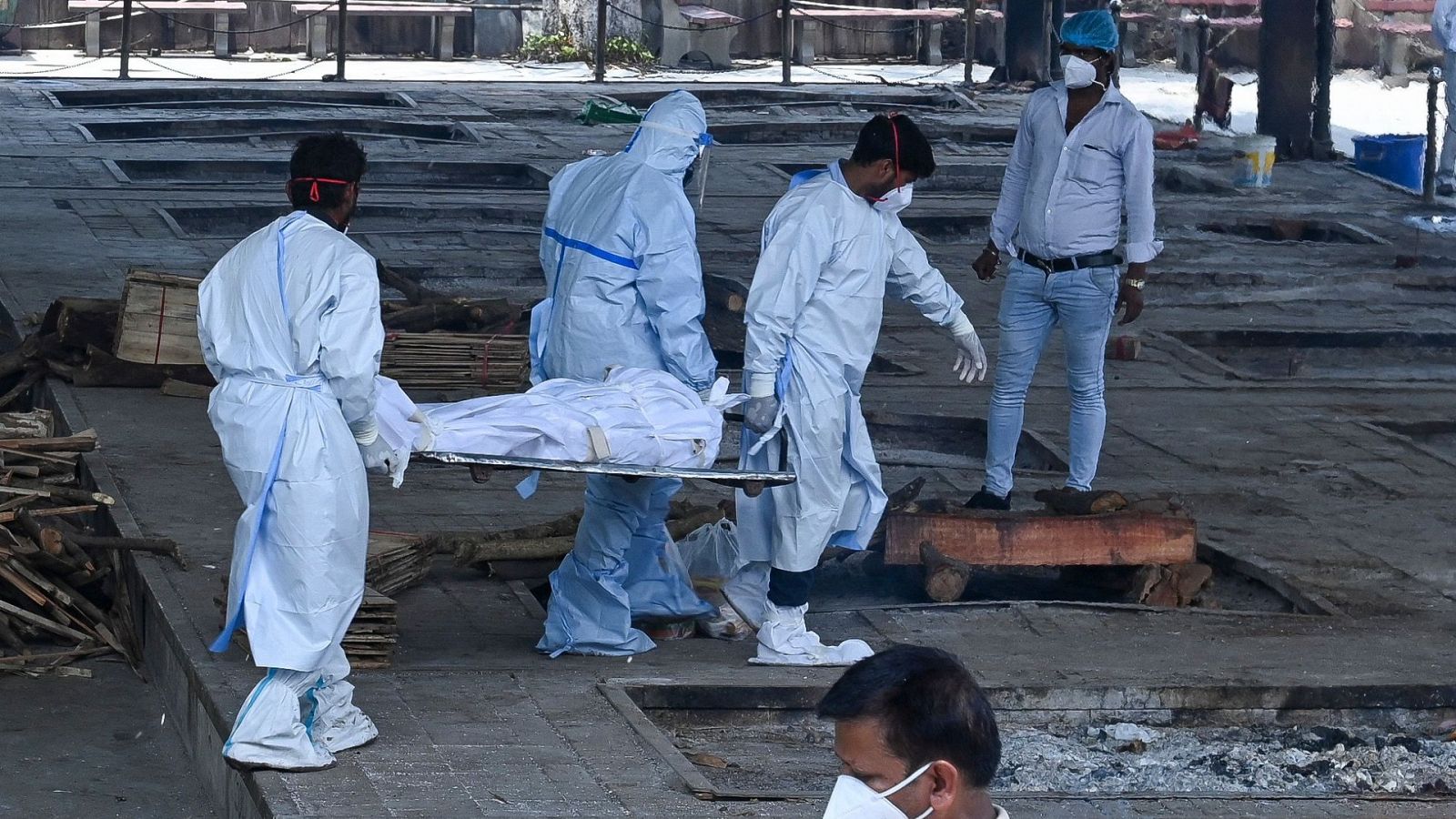 Personal sanitario traslada un cadáver de una persona fallecida por COVID-19 para su cremación, en Nueva Delhi (India)