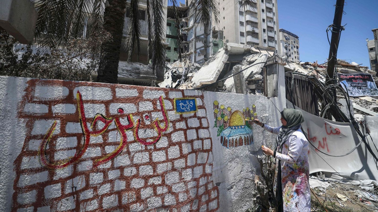 La artista palestina Etaf al-Najili pinta sobre un edificio dañado en Gaza