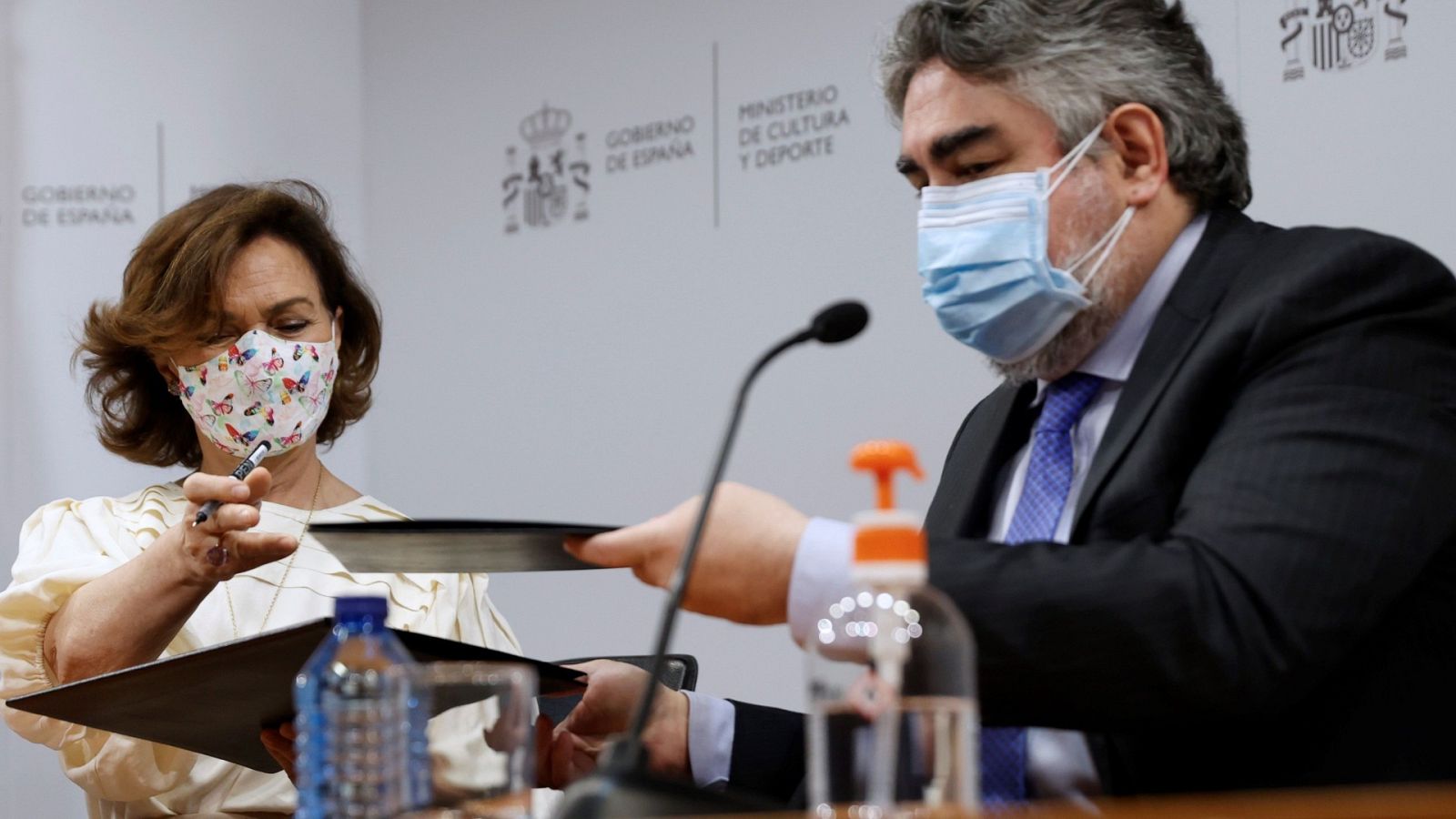 Carmen Calvo y José Manuel Rodríguez Uribes intercambian documentos durante la firma de un Convenio para digitalizar fondos documentales de interés para la Memoria Democrática