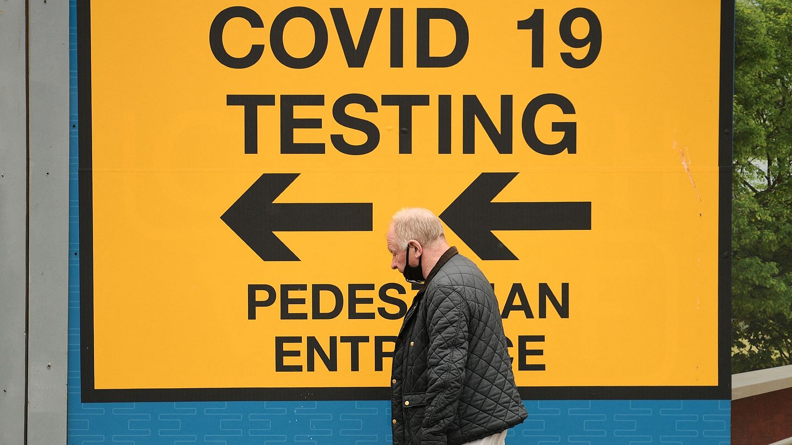 Un hombre pasa junto al cartel de un centro de pruebas COVID-19 en Bolton, Reino Unido.