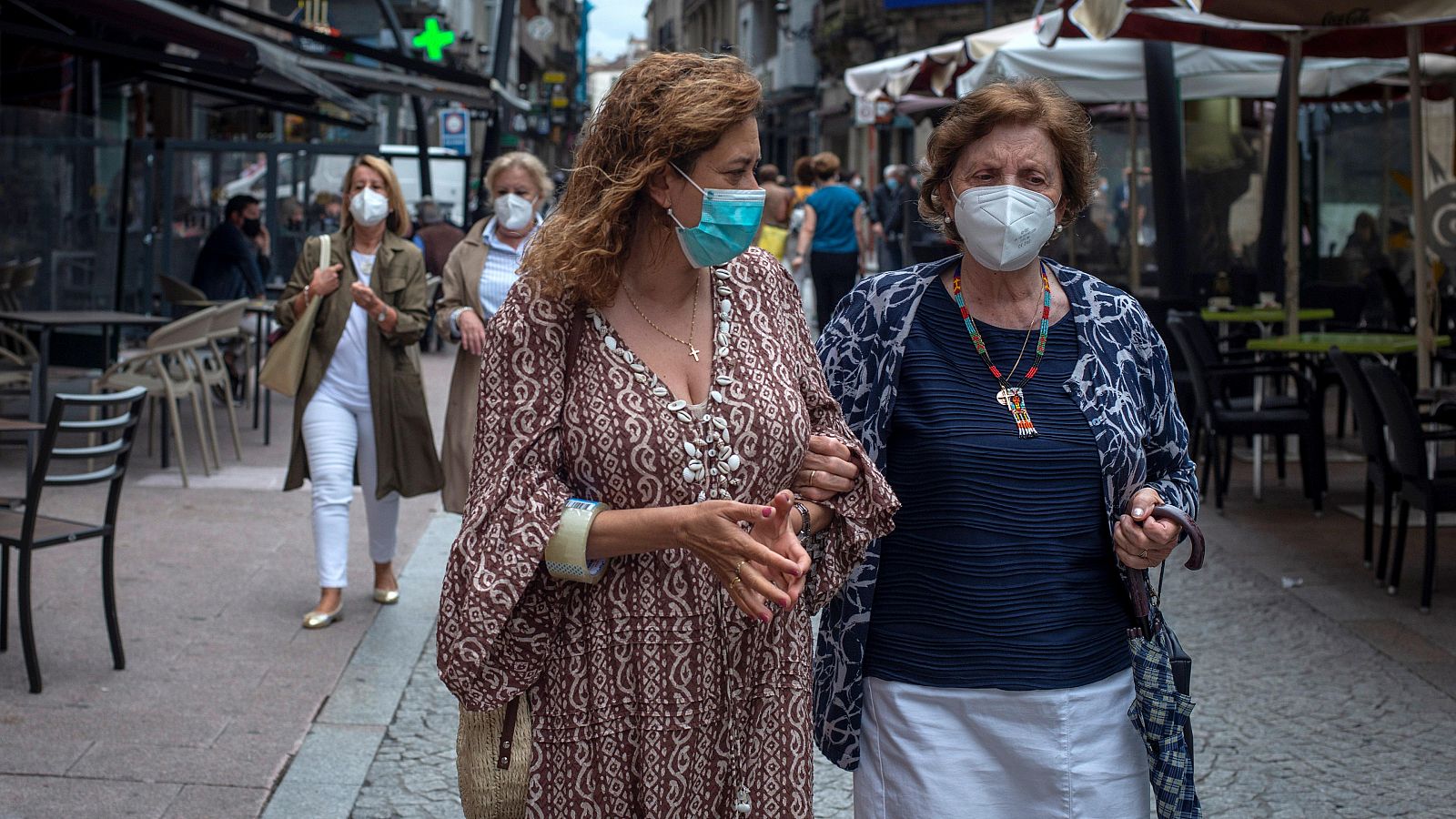 Dos mujeres caminan con mascarilla por la calle