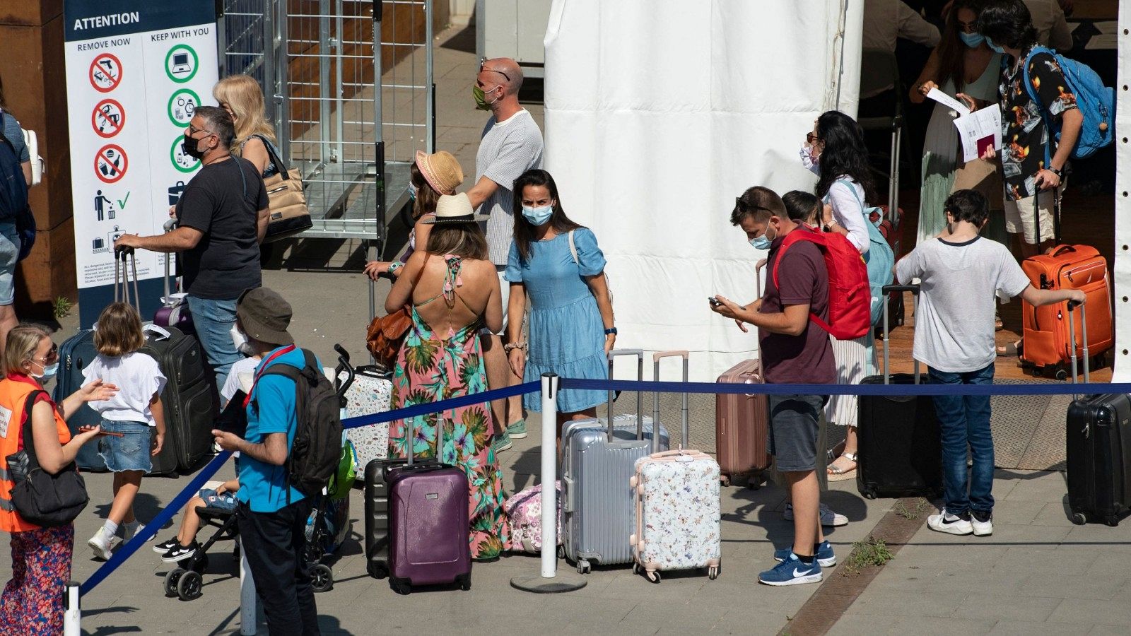 Un grupo de turistas con sus equipajes hacen cola
