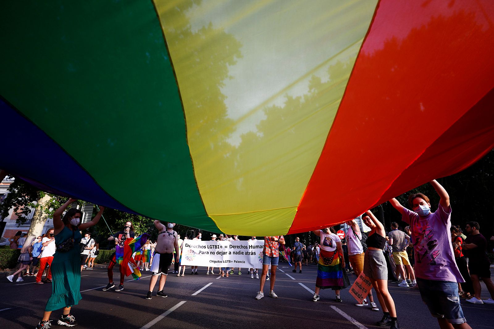 Participantes en la marcha del Orgullo LGTBI sostienen una enorme bandera del Orgullo.