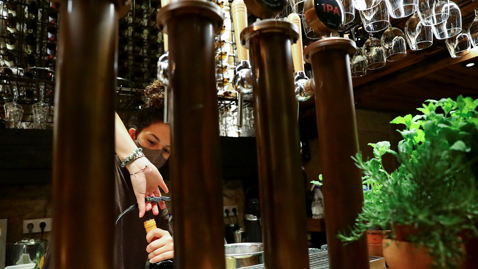 Una camarera descorcha una botella en un bar de Oporto, Portugal.
