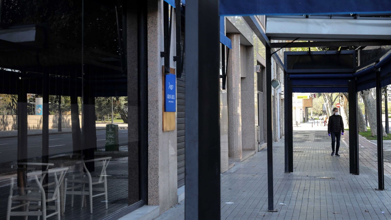 Una persona con mascarilla pasa delante de un restaurante cerrado, en Valencia, el 3 de abril de 2020.  