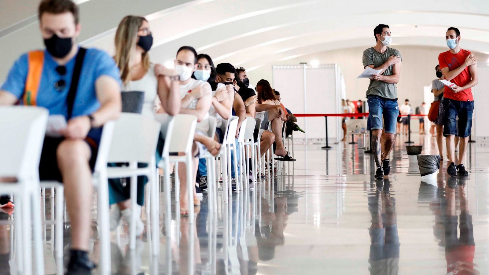 Varias personas esperan tras recibir su dosis de vacuna en la Ciudad de las Artes y las Ciencias de Valencia.