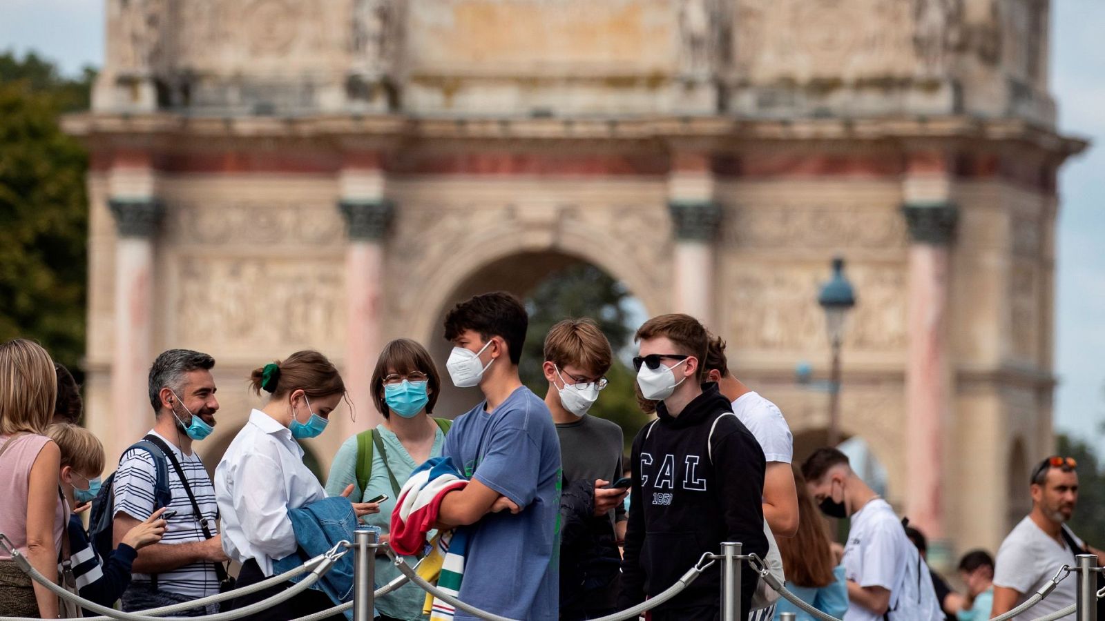 Turistas usando mascarillas mientras esperan para entrar al Museo del Louvre