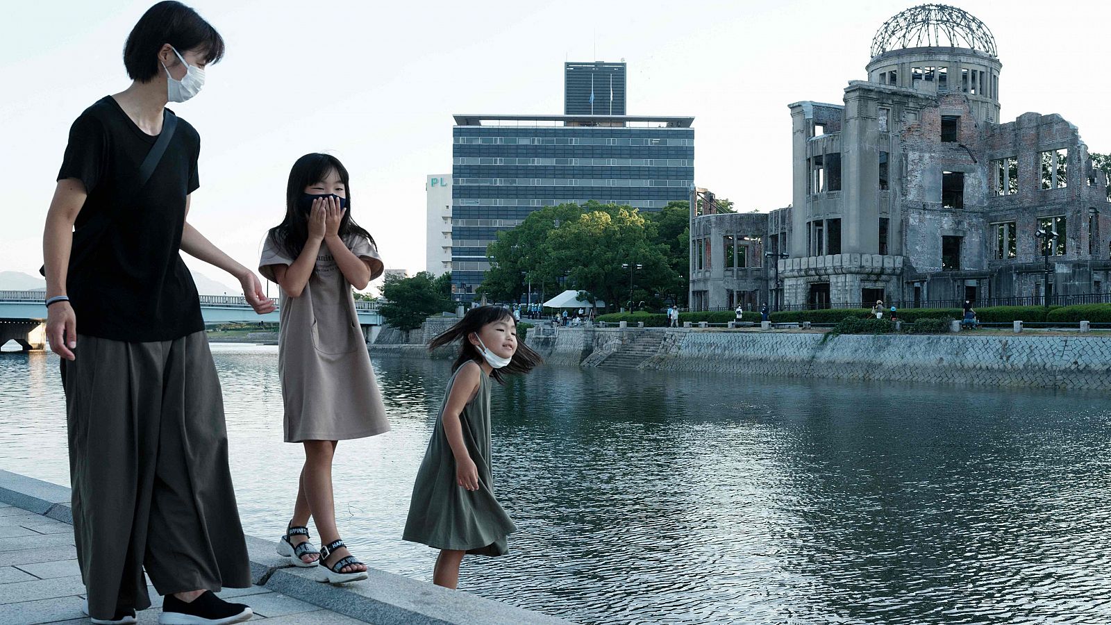 Rin Masuda, en el centro, y su hermana Kana -a la derecha- caminan a lo largo de las orillas del río Motoyasu con su madre frente a la Cúpula de la Bomba Atómica (atrás a la derecha) en Hiroshima el 6 de agosto de 2021.