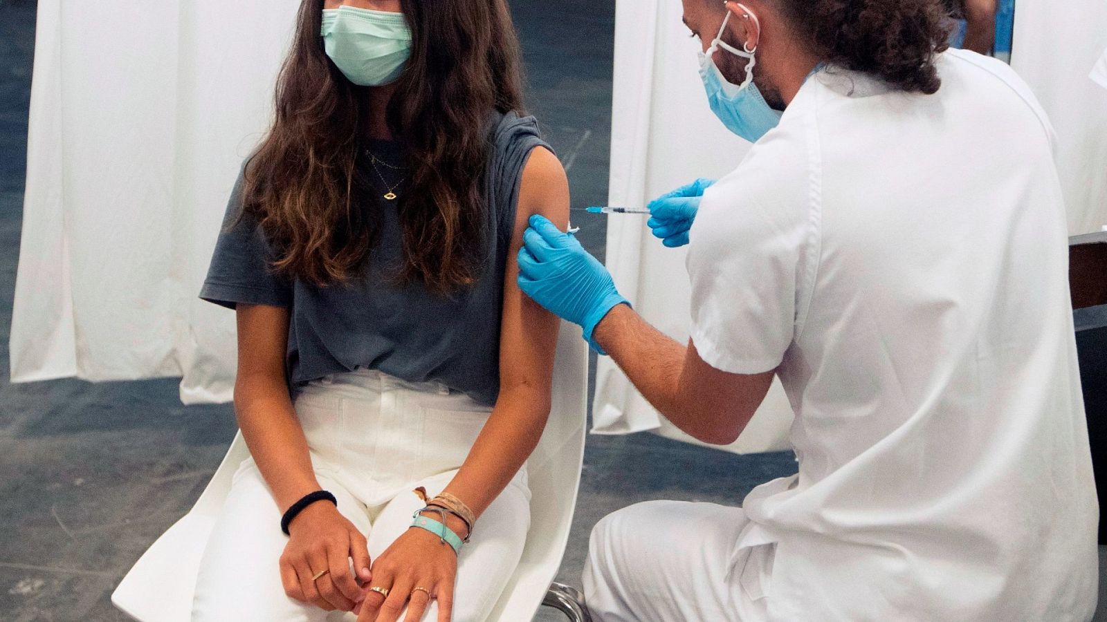 Un enfermero inocula una dosis de la vacuna contra el COVID a una adolescente en Barcelona.