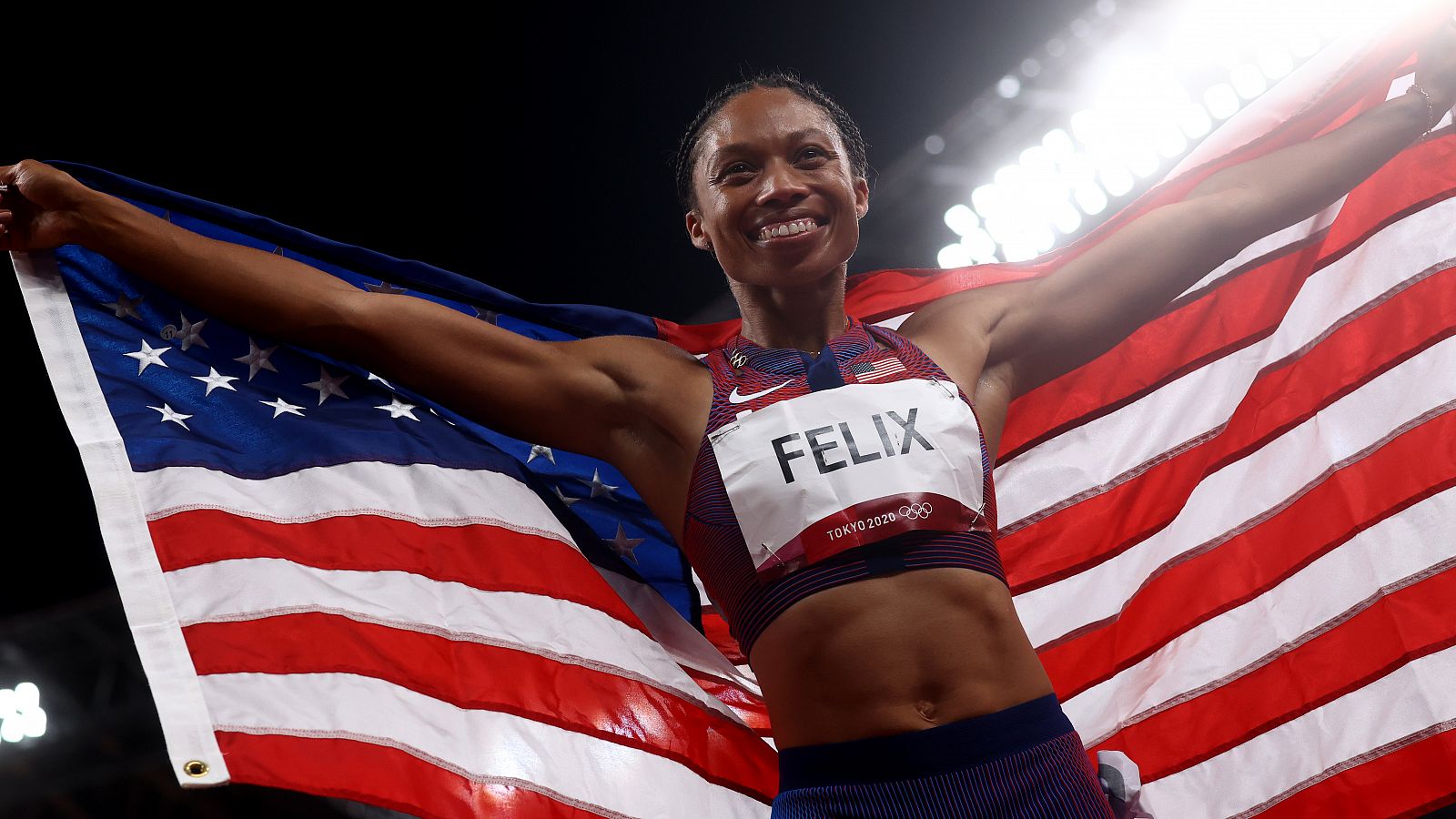 Allyson Felix, arropada con la bandera de Estados Unidos.