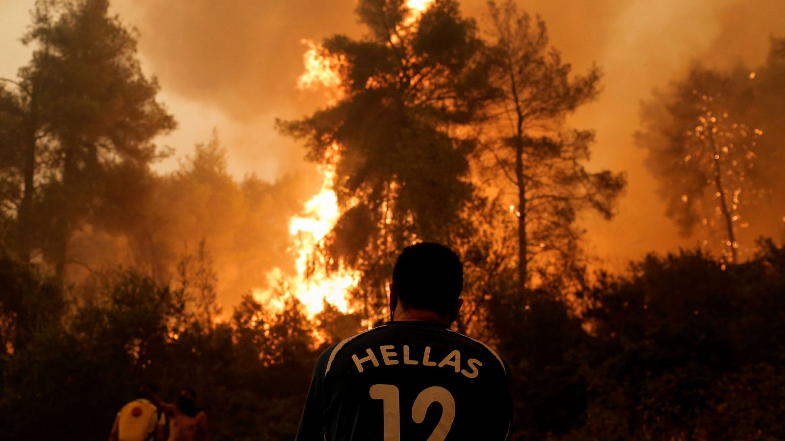 Una persona mira un incendio en la isla de Evia, en Grecia