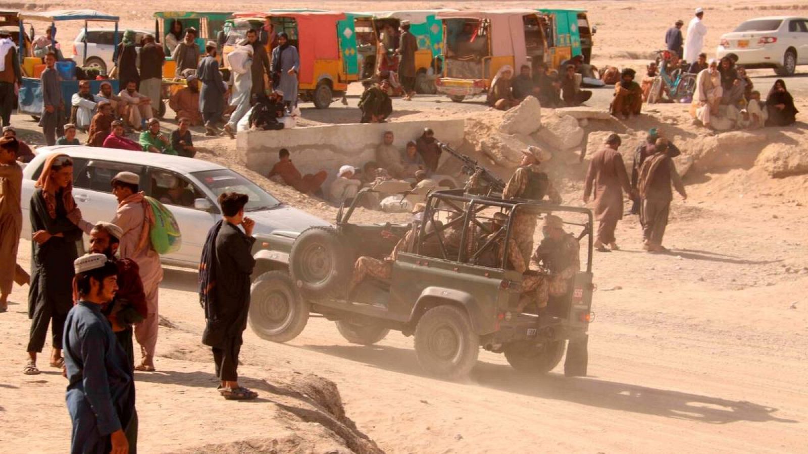 Funcionarios de seguridad pakistaníes montan guardia mientras las personas en la frontera entre Pakistán y Afganistán esperan su reapertura después de que fuera cerrada por los talibanes que han tomado el control del lado afgano de la frontera. en Ch