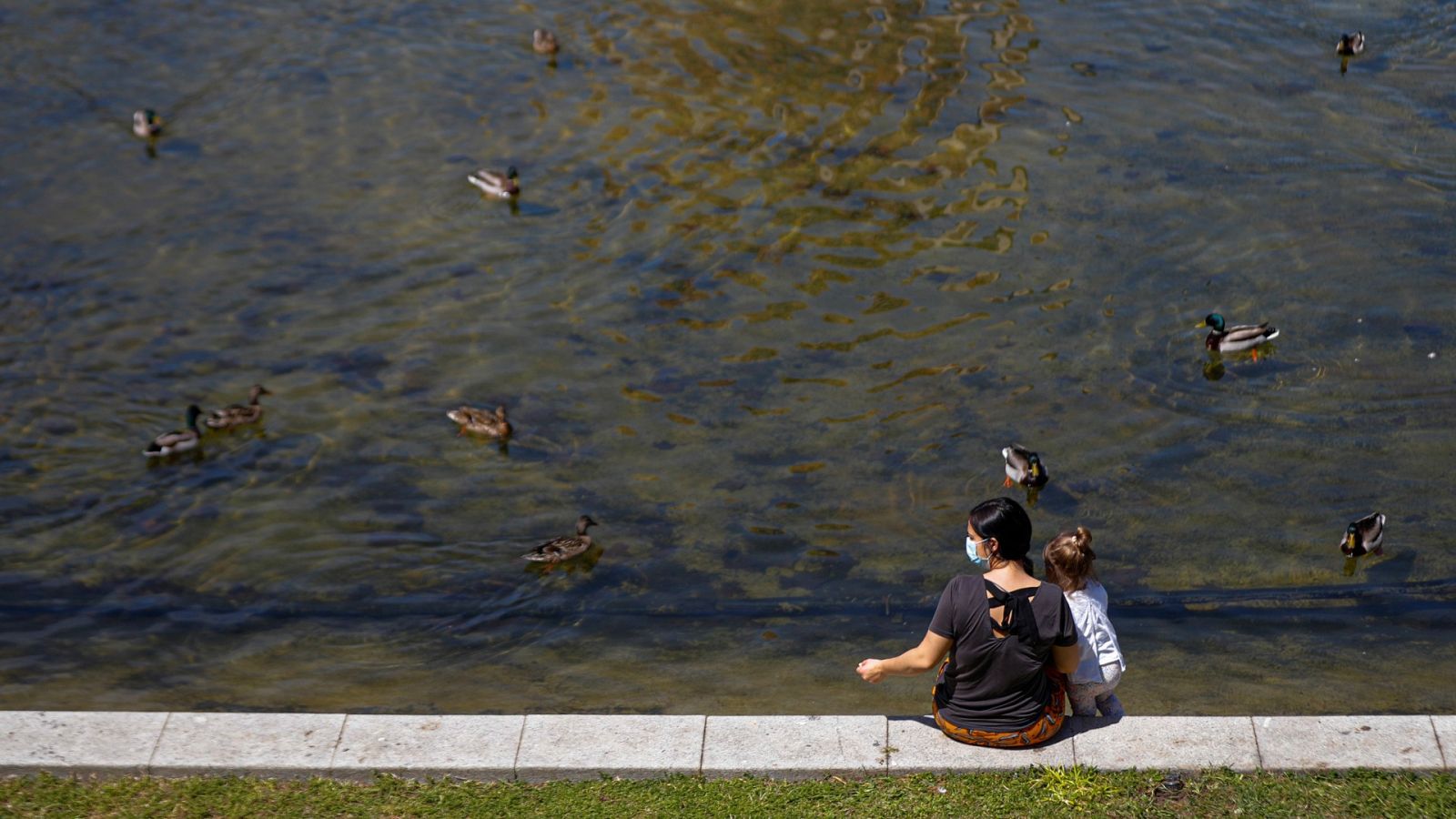 Una madre y su niña observan los patos a orillas del Río Manzanares, en Madrid