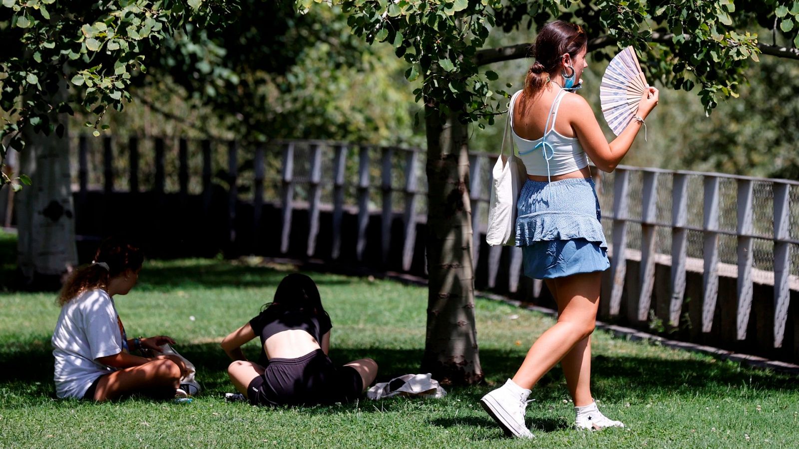 Una chica combate el calor con un abanico mientras pasea cerca de Madrid Río
