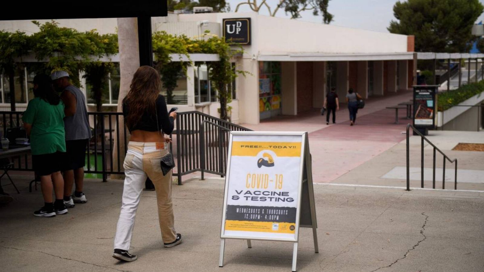 Una chica camina junto a un cartel que anuncia el punto de vacunación y el lugar donde hacerse test de COVID-19 en la ciudad de Long Beach en el campus de la Universidad Estatal de California en Long Beach (CSULB), en Long Beach, California, EE.UU.