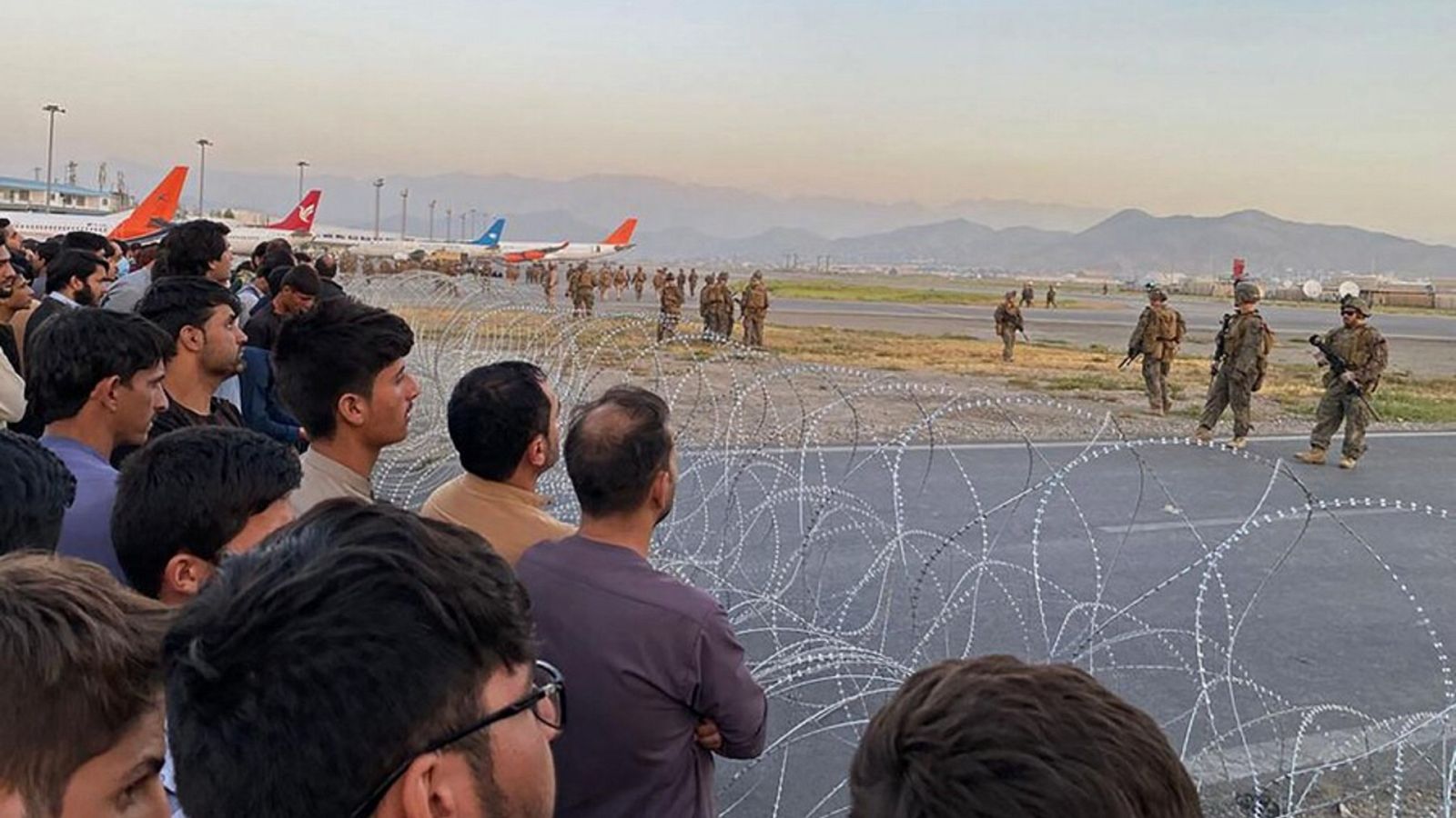 Afganos que intentan abandonar el país para huir de los talibanes se concentran tras una alambrada de espinos en el aeropuerto de Kabul. Enfrente, soldados de EE.UU. Shakib Rahmani / AFP