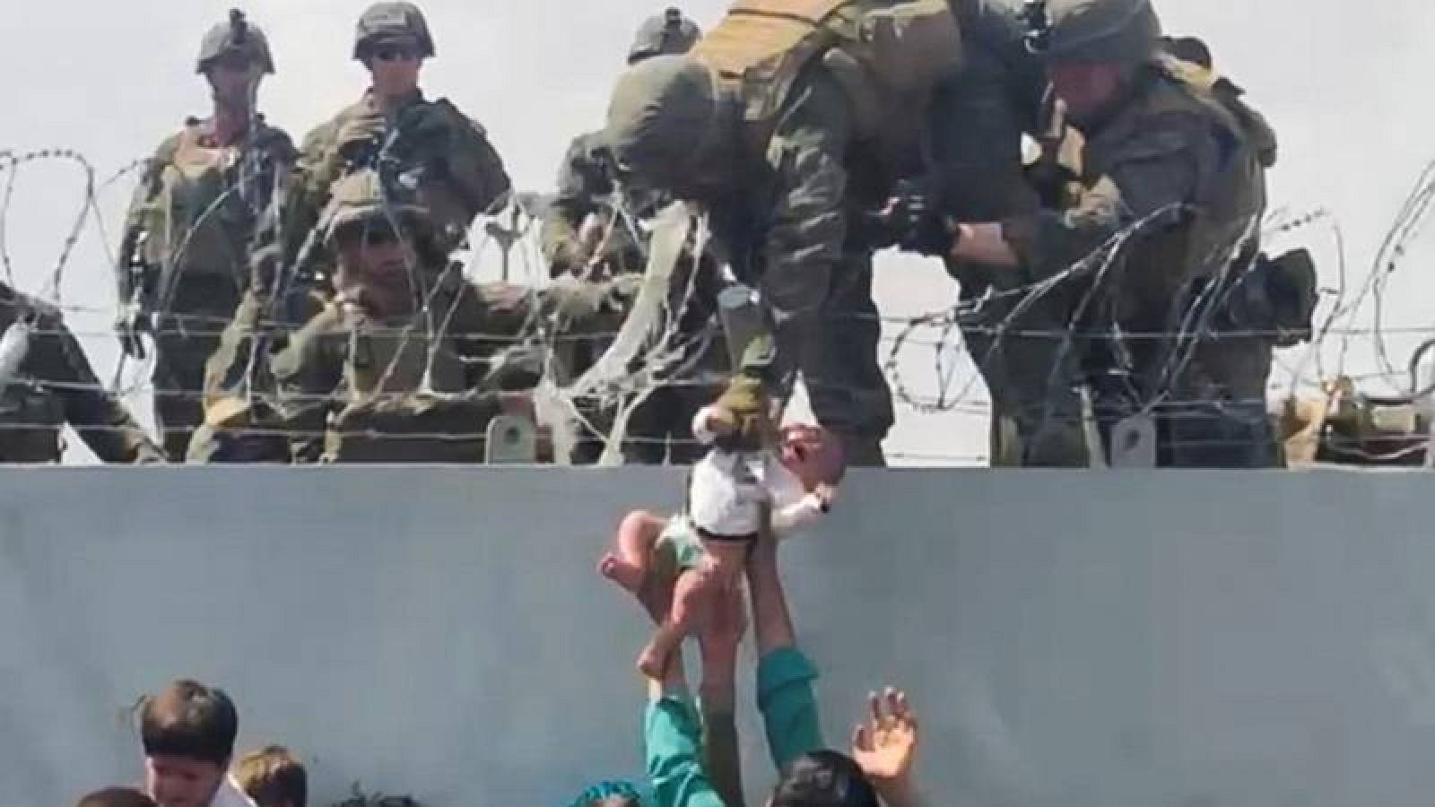 Un hombre entrega un bebé a un soldado estadounidense a través del muro perimetral del aeropuerto de Kabul