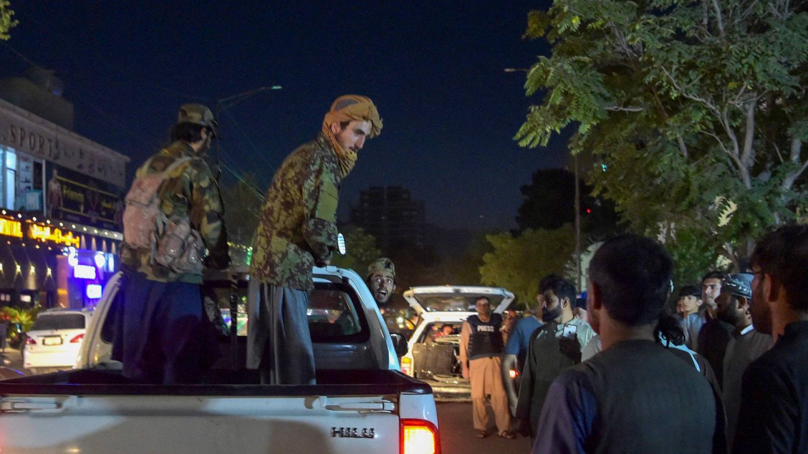 Los talibanes en una camioneta frente a un hospital mientras los voluntarios llevan a los heridos para recibir tratamiento después de las dos explosiones