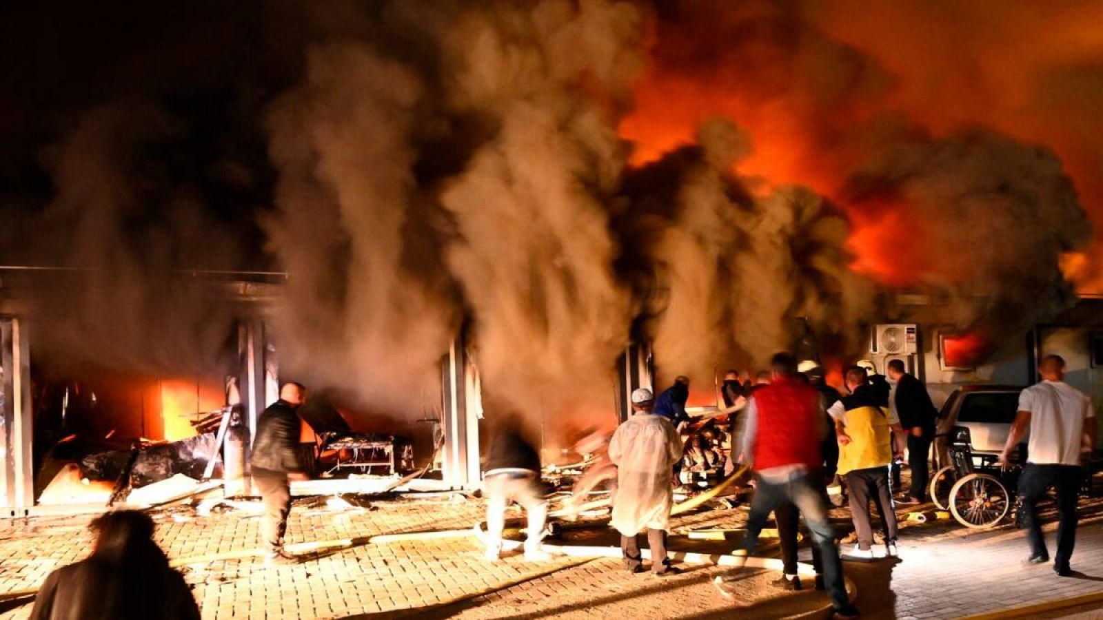 El humo se eleva cuando los bomberos y civiles intentan extinguir un incendio que estalló en un hospital para pacientes con COVID-19 en Tetovo, República de Macedonia del Norte. 