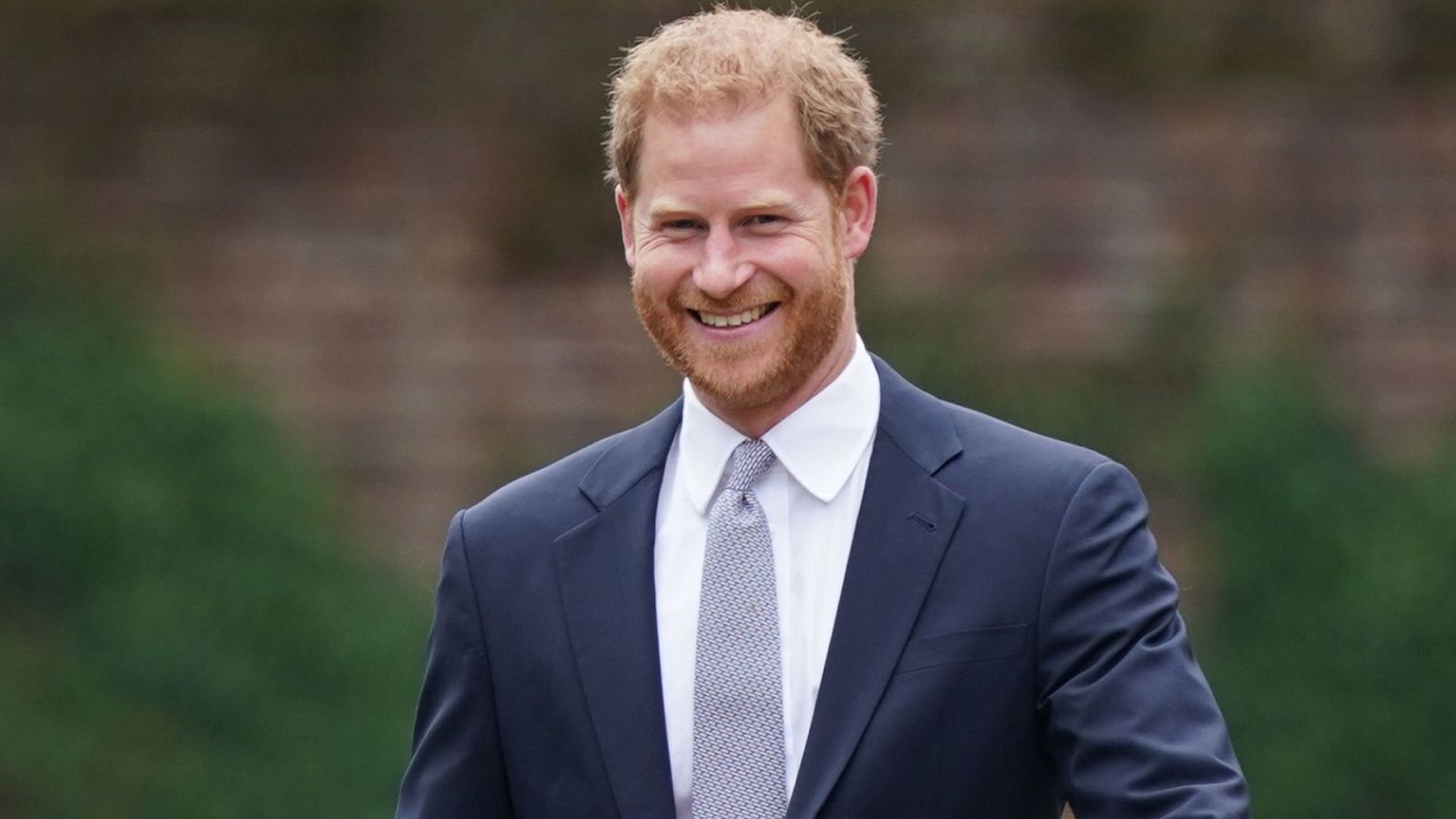 El príncipe Harry sonríe a cámara vestido de traje y corbata