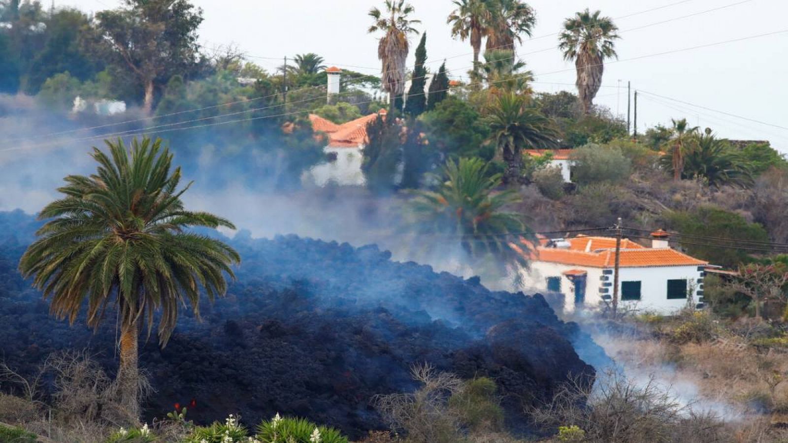 El humo se eleva mientras la lava fluye junto a las casas tras la erupción de un volcán en el parque nacional Cumbre Vieja, en la zona residencial de Los Campitos en Los Llanos de Aridane, en la isla canaria de La Palma, España.  