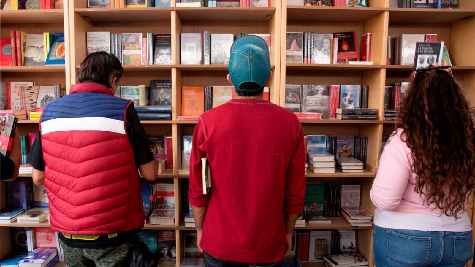 Tres jóvenes consultan libros en una librería.