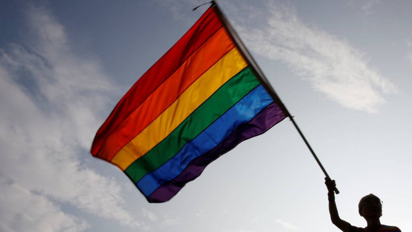 Un hombre sostiene una bandera del orgullo gay. 