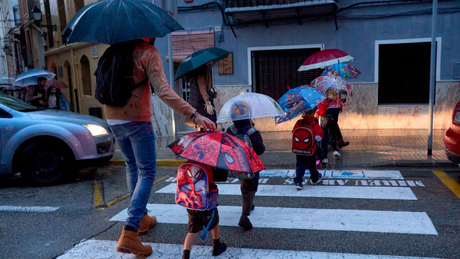 Imagen de archivo del 22 de octubre de 2021 de varias personas con paraguas cruzando una calle de Gandía (Valencia).
