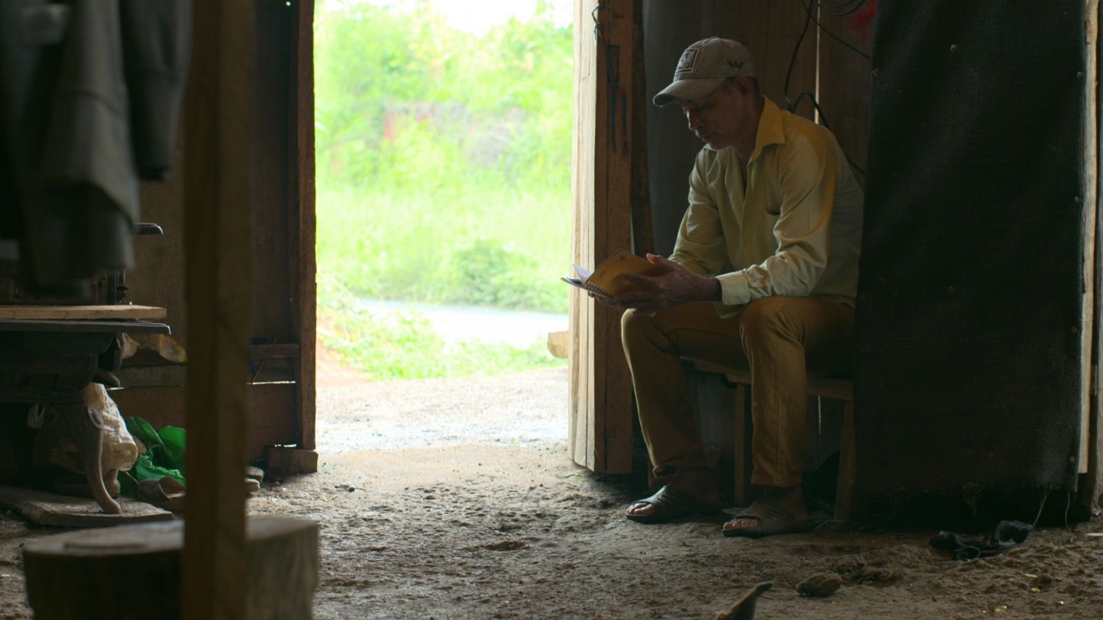 Campesino nicaragüense exiliado en Costa Rica sentado dentro de una casa precaria con suelo de tierra.