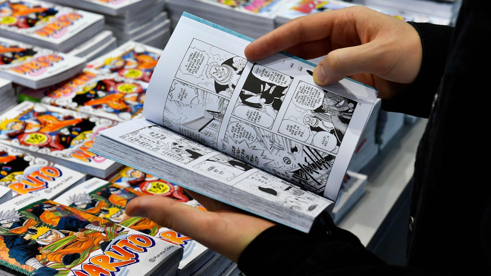 Persona leyendo en el stand de mangas de One Piece y Naruto