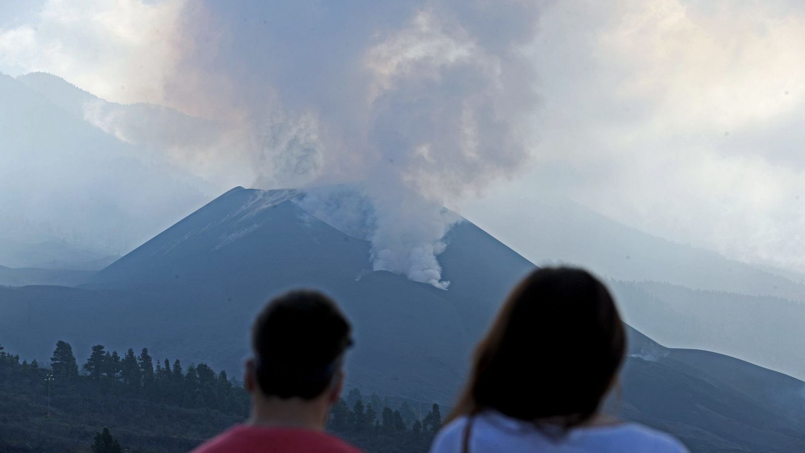 Una pareja observa el volcán y la nube de gases este jueves desde el mirador de Tajuya.