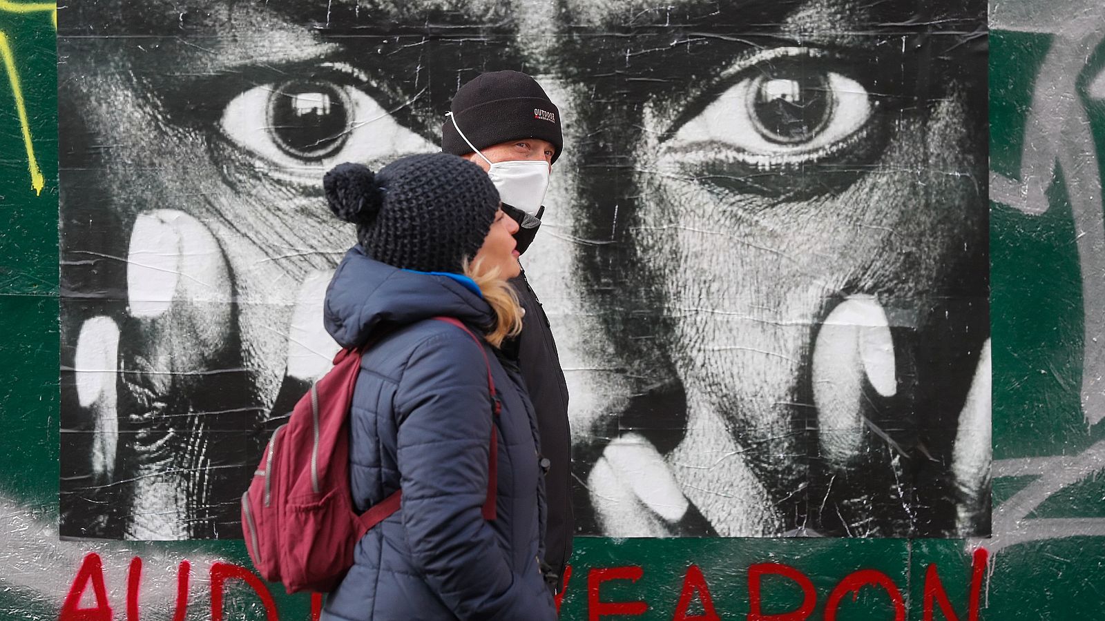Una pareja pasa junto a una foto de Miles Davis en el centro de Kiev, Ucrania.