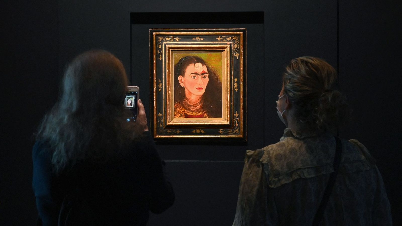 El autorretrato Diego y yo, de Frida Kahlo, en la sala de exposiciones mientras dos personas lo contemplan