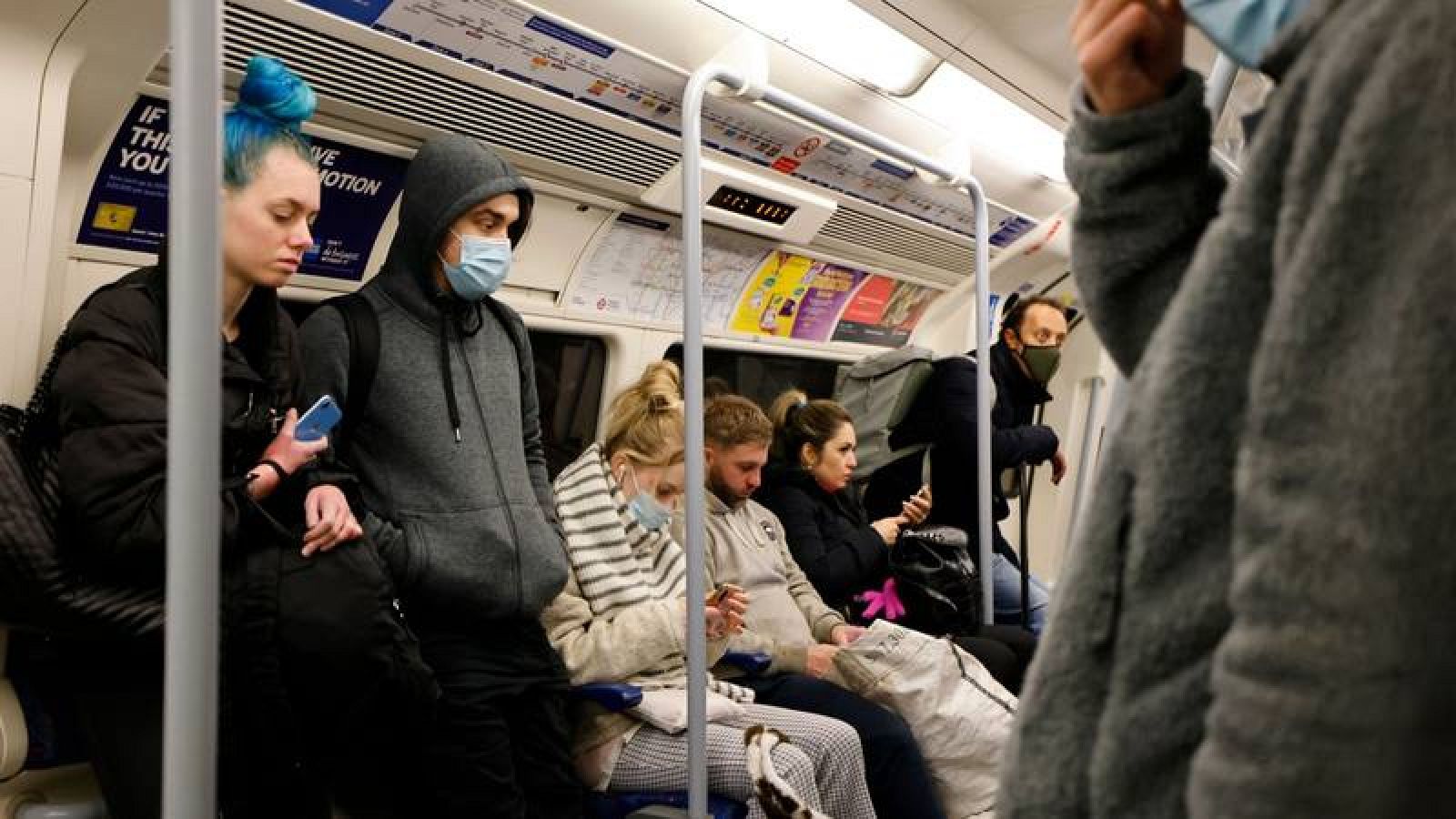 Viajeros en el metro de Londres, algunos con mascarilla por la pandemia de COVID-19