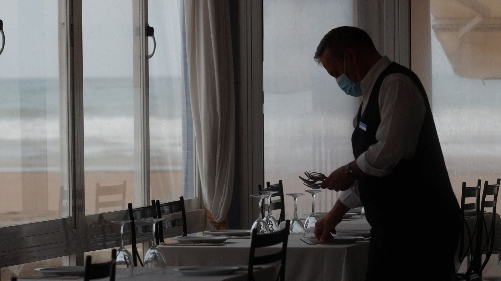 Un camarero prepara una mesa en un restaurante en la playa de la Malvarrosa, en Valencia