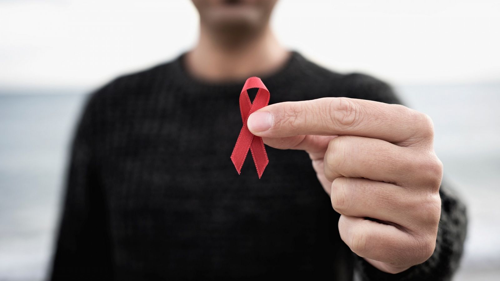 Un hombre sostiene un lazo rojo, símbolo en apoyo a la lucha contra el sida