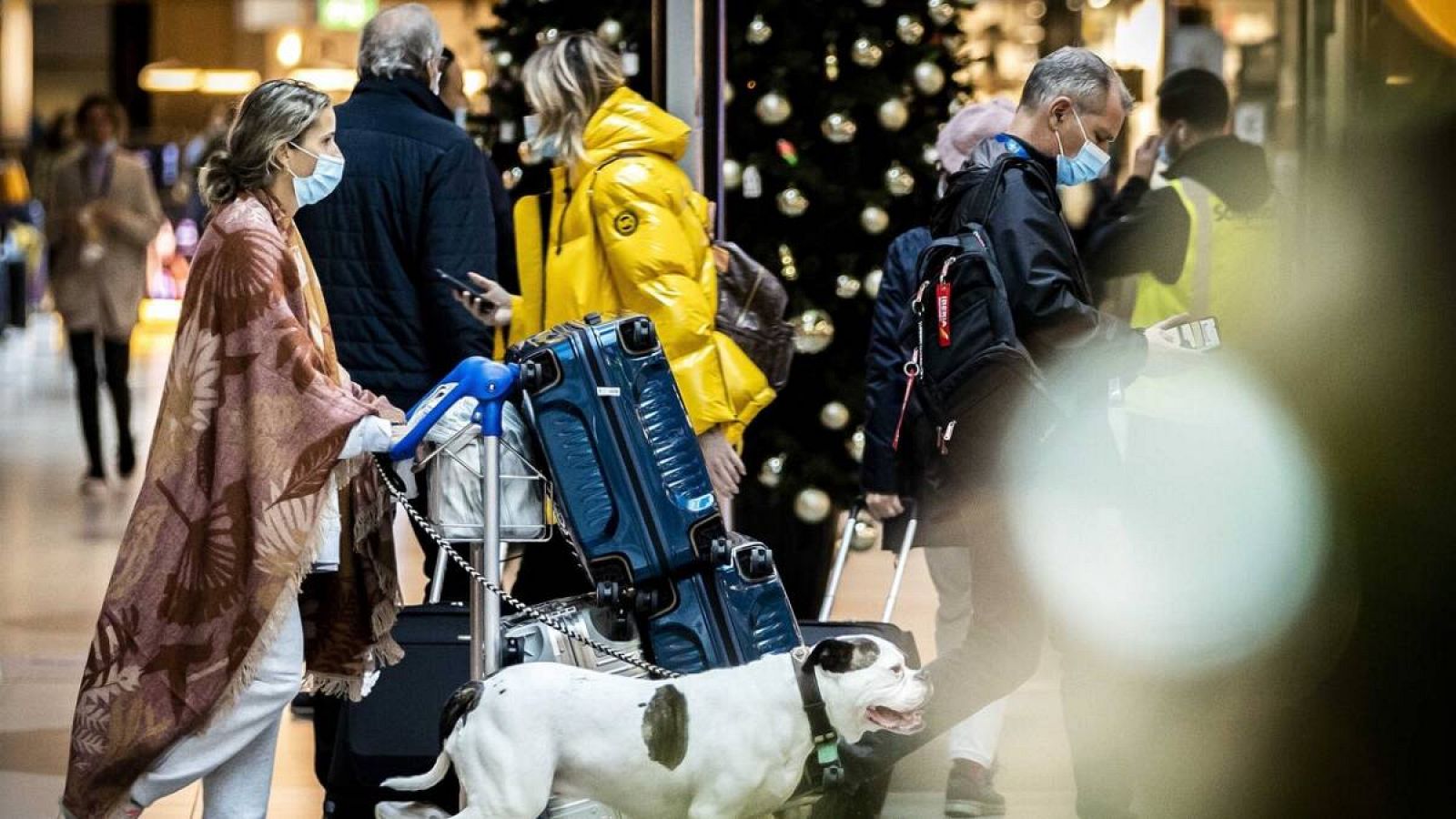 Pasajeros en el aeropuerto de Schiphol usan mascarillas mientras caminan en una terminal decorada de Navidad en el aeropuerto de Ámsterdam, Países Bajos.