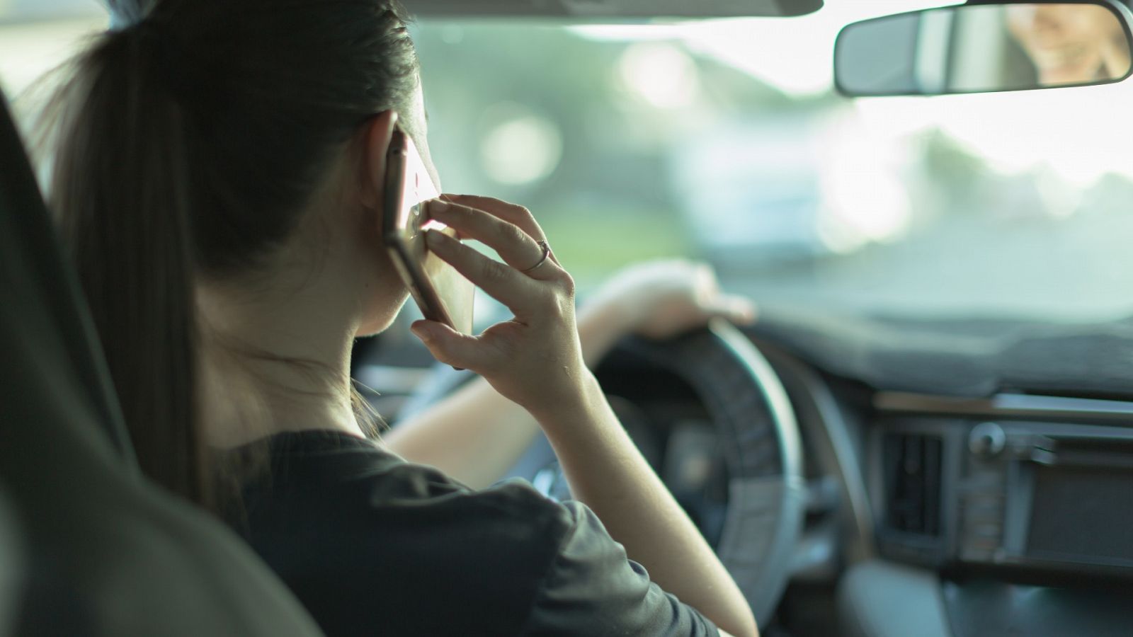 Una mujer habla por teléfono mientras conduce