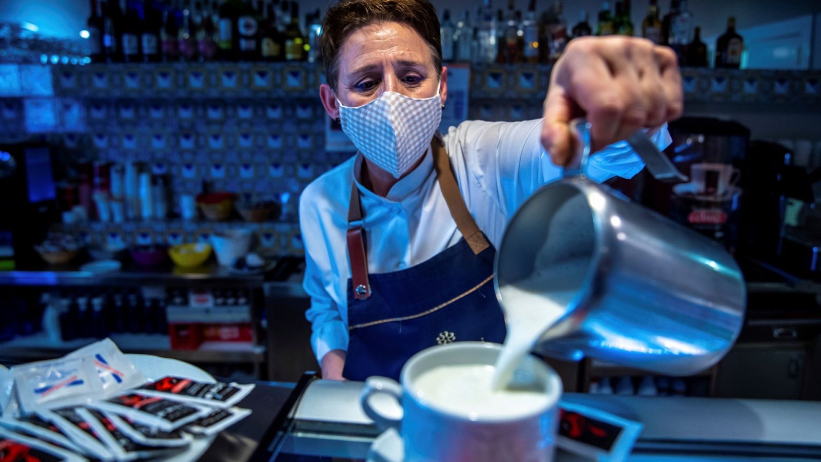 Una camarera sirve un café con leche en un bar