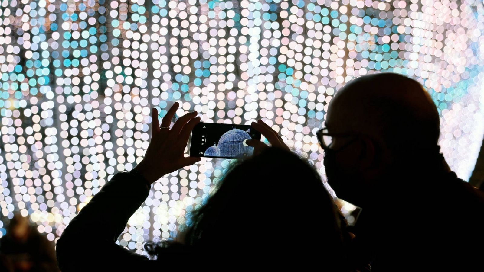Varias personas fotografían una inmensa bola iluminada de los adornos de Navidad en Valencia