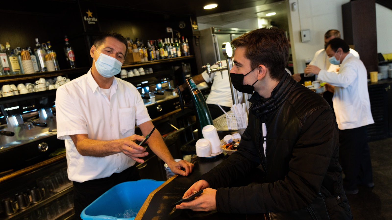 Un joven presenta el pasaporte COVID en una cafetería de Barcelona