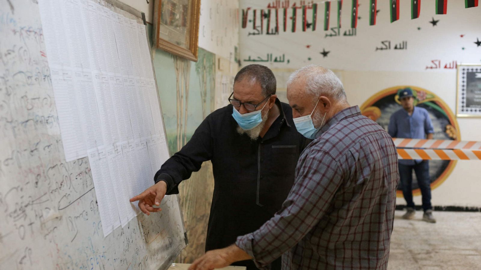 Dos hombres comprueban sus nombres en el censo expuesto en en un colegio electoral de Trípoli