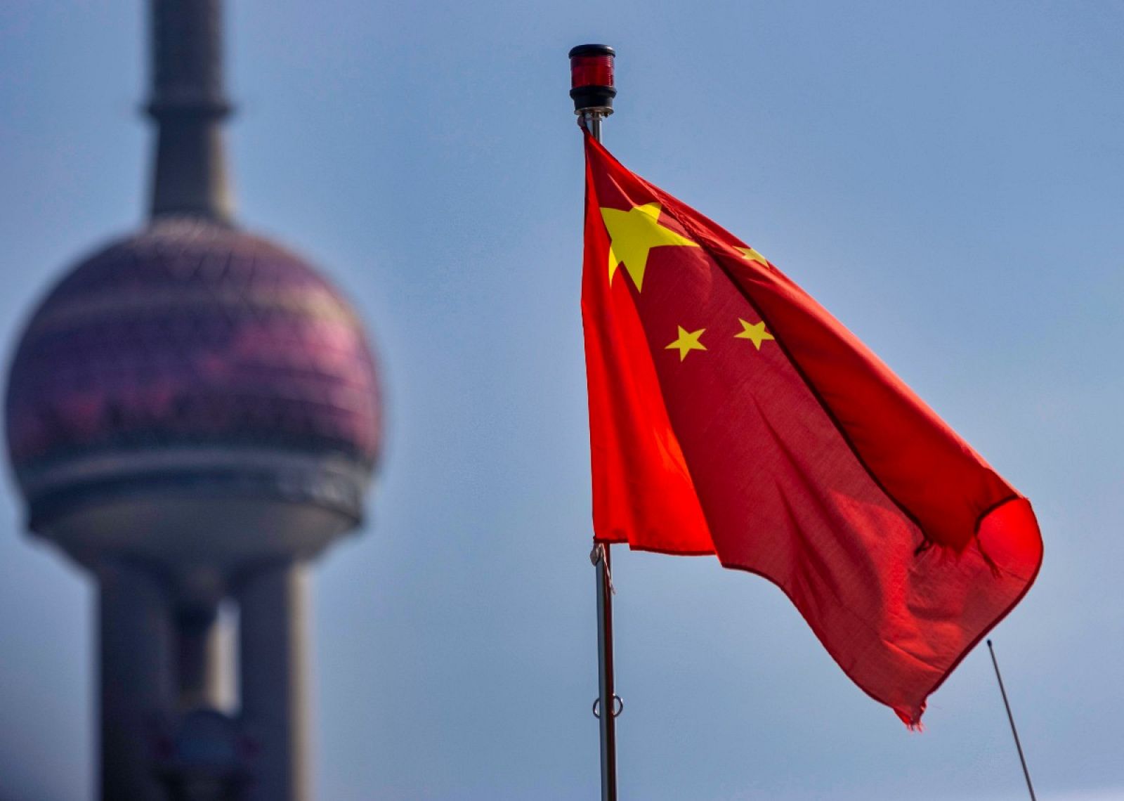 La bandera china frente a una torre de televisión en Shanghai