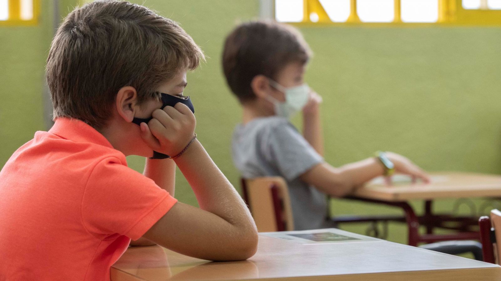 Dos niños atienden en clase con las mascarillas puestas